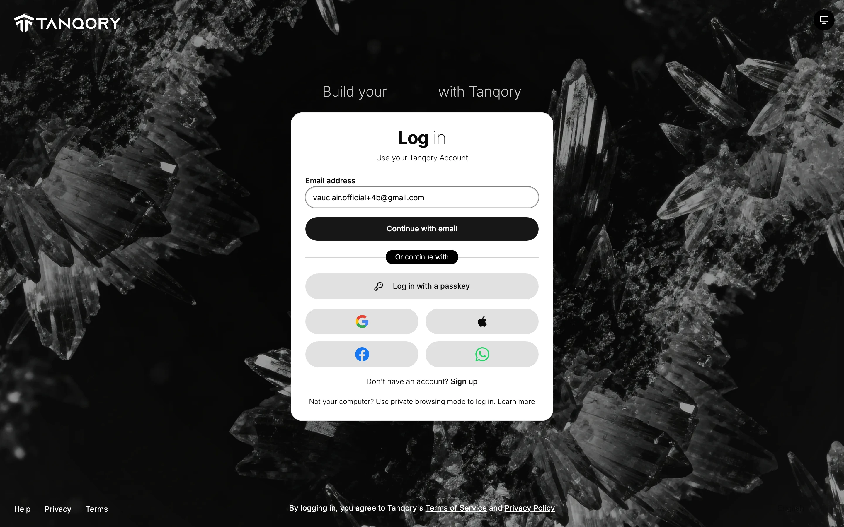 The log-in page, which is where both routes start: a Log in heading over Use your Tanqory Account, an Email address field, a Continue with email button, a divider reading Or continue with, then Log in with a passkey and buttons for Google, Apple, Facebook and WhatsApp, and at the foot the line Don't have an account? Sign up.